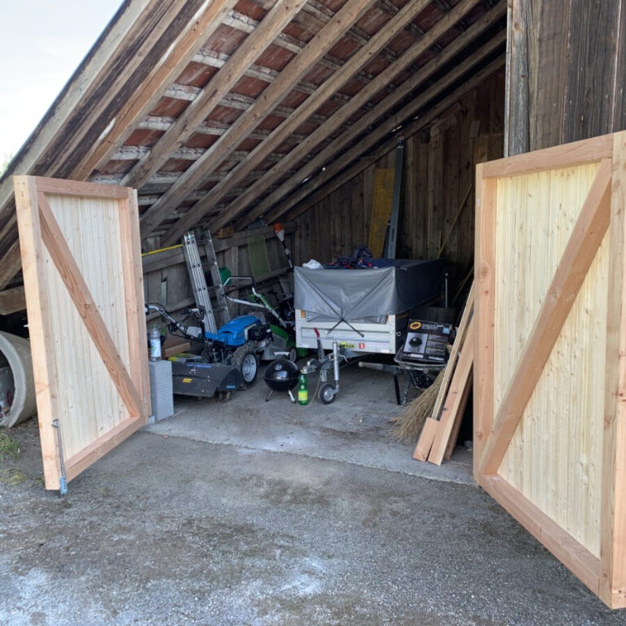 Zwei neue Holztore mit Diagonalstreben an einem Schuppen
